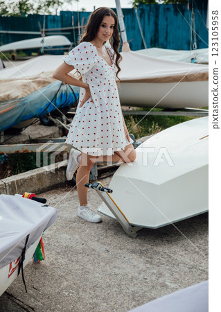 Beautiful brunette woman in summer dress by the boat in the yacht club Beautiful brunette woman in summer dress by the boat in the yacht club 123105958