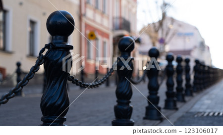 Iron posts with chains, fences by the road. An old, vintage fence Iron posts with chains, fences by the road. An old, vintage fence 123106017