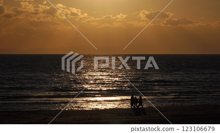 Sparkling sea in the evening and silhouette of three people walking on the shore, winter, telephoto, 250103pm 123106679