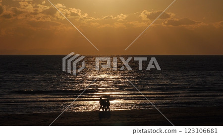 Sparkling sea in the evening and silhouette of three people walking on the shore, winter, telephoto, 250103pm 123106681
