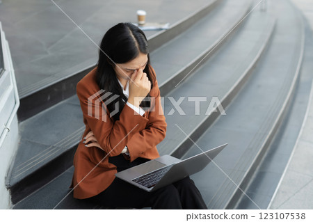 Stressed businesswoman struggling with financial crisis on laptop, dealing with customer dissatisfaction, corporate failure, and workplace challenges. 123107538