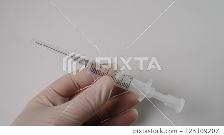 A hand holding a syringe filled with liquid, showcasing medical equipment for health and vaccination. A hand holding a syringe filled with liquid, showcasing medical equipment for health and vaccination. 123109207