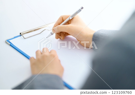 Part cut of a young woman holding a clipboard answering a questionnaire. Filming cooperation: SKY Perfect Tokyo Media Center 123109760