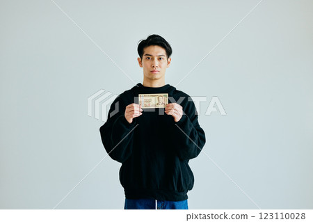 A young man in his twenties holding a 10,000 yen bill 123110028