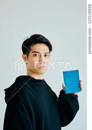 A young man in his 20s holding a pension book 123110038