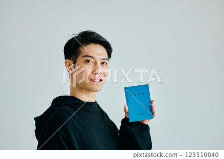 A young man in his 20s holding a pension book 123110040