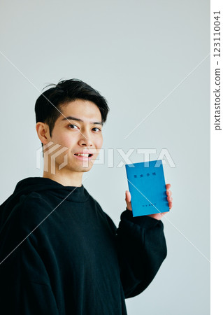 A young man in his 20s holding a pension book 123110041