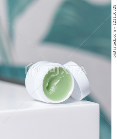 Opened white blank lip balm jar on wash basin in green tropical bathroom close up, cosmetic mockup Opened white blank lip balm jar on wash basin in green tropical bathroom close up, cosmetic mockup 123110329