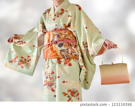 Upper body of a woman wearing a formal kimono, carrying a Japanese bag and spreading her arms_White light bokeh background 123110398