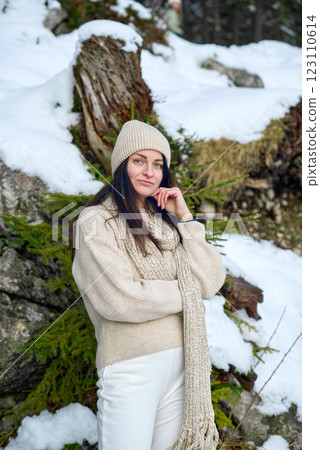 Serene Winter Portrait: Young Woman in Cream Sweater Contemplating Snowy Mountain Landscape with Evergreen Forest 123110614