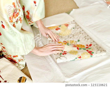 A woman's hands wrapping a kimono sash in wrapping paper A woman's hands wrapping a kimono sash in wrapping paper 123110621
