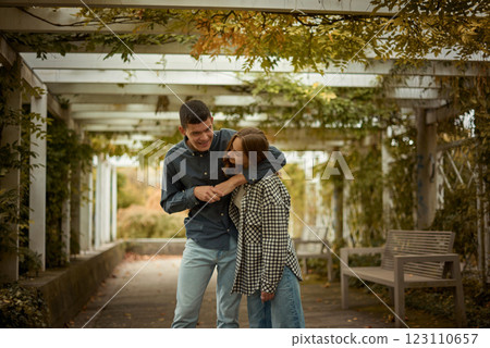 Young Cute Female Hugs Boyfriend. In Autumn Outdoor. Lovers Walking in Park. Attractive Funny Couple. Lovestory in Forest. Man and Woman. Cute Lovers in the Park. Family Concept. Happy Couple. 123110657