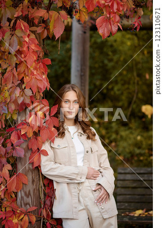 Autumn Portrait: Stylish Young Woman in Beige Outfit Posing by Wooden Pergola with Red Autumn Leaves. Cozy Fall Portrait in Scenic Garden Setting Showcasing Natural Warmth and Seasonal Beauty Autumn Portrait: Stylish Young Woman in Beige Outfit Posing by Wooden Pergola with Red Autumn Leaves. Cozy Fall Portrait in Scenic Garden Setting Showcasing Natural Warmth and Seasonal Beauty 123110671