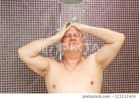 A large white man stands happily in the shower with soap on his head 123111424