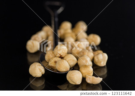 Peeled nut kernels on a spoon with a black background Peeled nut kernels on a spoon with a black background 123111642