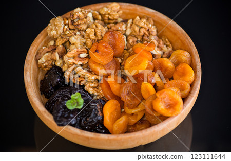 Prunes, dried apricots and nuts in a wooden bowl on a dark background 123111644