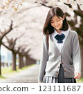 一名身穿制服的女孩沿著一排櫻花樹行走 123111687