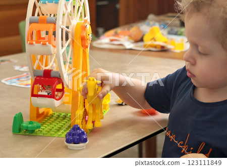 Child plays with a plastic constructor at home on table. Children and educational games. Animals of Africa and an amusement park. Child plays with a plastic constructor at home on table. Children and educational games. Animals of Africa and an amusement park. 123111849