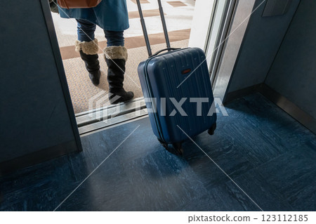 一位女士拉著行李箱走下電梯的背影 123112185