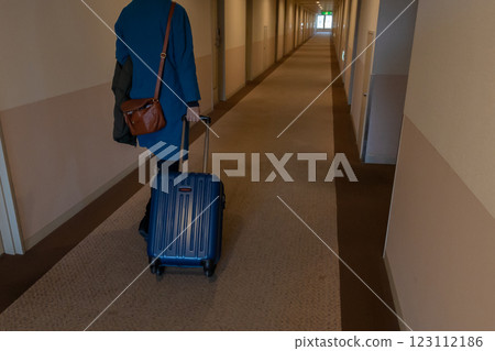一位女士拉著行李箱走在飯店走廊的背影 一位女士拉著行李箱走在飯店走廊的背影 123112186