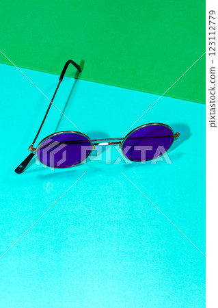 Purple round sunglasses on a blue and green background 123112779