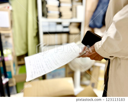 Hands of an elderly woman holding handwritten manuscript paper 123113183