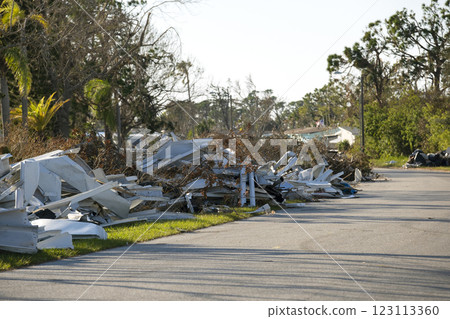Piles of rubbish on street side from severely damaged houses after hurricane in Florida mobile home residential area. Consequences of natural disaster 123113360