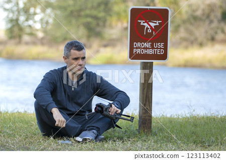 Operator is disappointed because he can not fly his quadcopter in national park no drone area. Man is unable to use his UAV near restriction notice sign 123113402