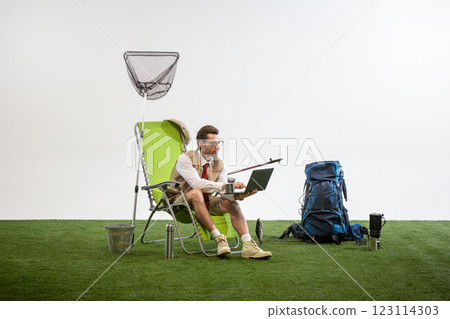 Businessman sitting on chair working on laptop while holding coffee cup against white studio background. Businessman sitting on chair working on laptop while holding coffee cup against white studio background. 123114303