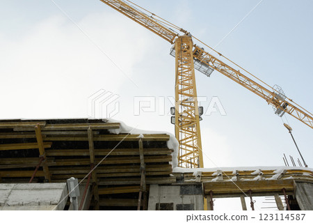 Yellow Tower Crane at Winter Construction Site with Structural Framework 123114587