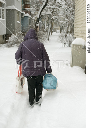 Woman Carrying Groceries Through Snowy Street in Winter 123114589