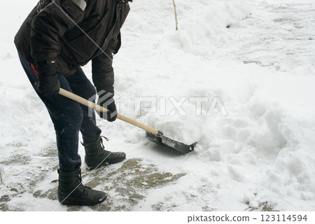 Person Clearing Snow with Shovel on Cold Winter Day 123114594