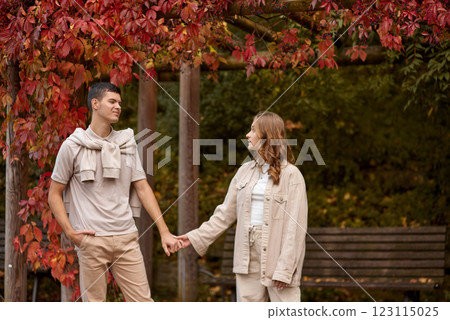 Young couple in love walking in the autumn park holding hands looking in the sunset. Loving couple holding hands while walking at sunset. The hands of the male and female lovers who hold hands walk Young couple in love walking in the autumn park holding hands looking in the sunset. Loving couple holding hands while walking at sunset. The hands of the male and female lovers who hold hands walk 123115025