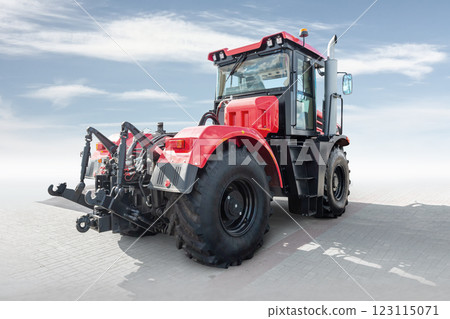 Red heavy wheeled tractor isolated on bright background with sky 123115071