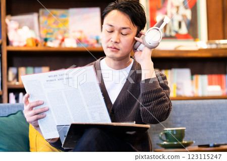 A middle-aged man listening to a record through headphones 123115247