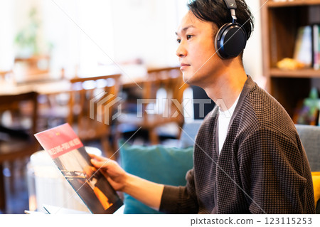 A middle-aged man listening to a record through headphones 123115253