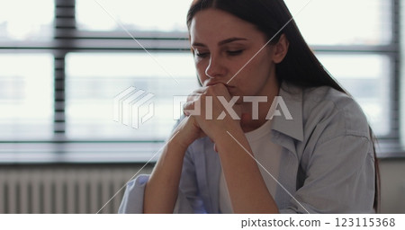 Young woman sitting on sofa, looks pessimistic and sad, almost crying, man calming her down, softly touches and hugs her. Partnership and support concept. Young woman sitting on sofa, looks pessimistic and sad, almost crying, man calming her down, softly touches and hugs her. Partnership and support concept. 123115368