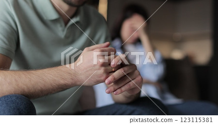 Close up a man wiggles his wedding ring on his finger while talking to his wife. Close-up of his hand. Relationship crisis. Close up a man wiggles his wedding ring on his finger while talking to his wife. Close-up of his hand. Relationship crisis. 123115381