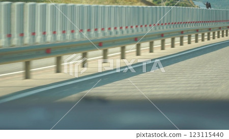 A blurry shot of a highway with a red and white barrier. 123115440