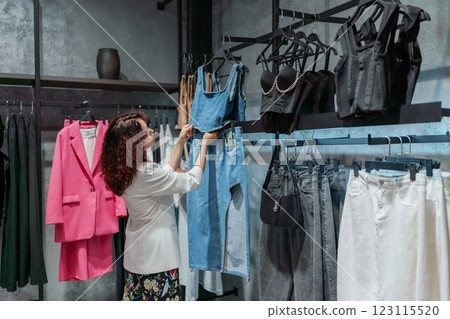 Shopping woman, women's fashion clothes in a store, boutique. Woman choosing clothes in a store 123115520