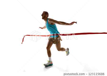 Dynamic photo of young man, runner breaking red ribbon, ultimate triumph and endurance captured in motion against white studio background. Dynamic photo of young man, runner breaking red ribbon, ultimate triumph and endurance captured in motion against white studio background. 123115686