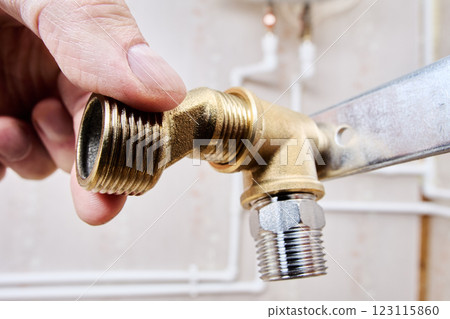 Plumber is assembling brass elbow fitting and an eccentric reducer, securing them to mounting bracket for stable and leak proof connection. 123115860