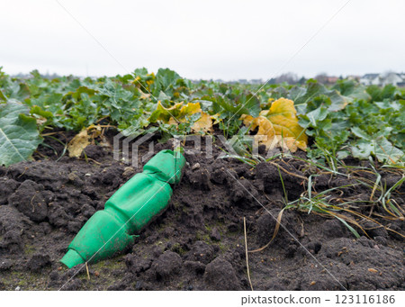 Crushed Green Plastic Bottle Polluting Agricultural Soil Crushed Green Plastic Bottle Polluting Agricultural Soil 123116186