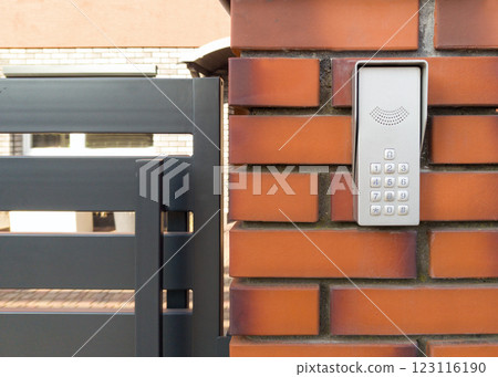 Modern Intercom Keypad on Brick Wall by Metal Gate Modern Intercom Keypad on Brick Wall by Metal Gate 123116190