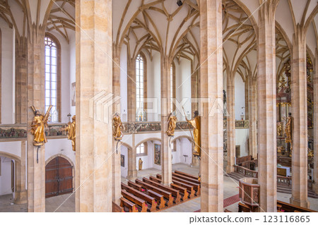 The interior showcases late Gothic design with tall pillars and intricate details. Golden statues adorn the walls, while the serene ambiance invites reflection and admiration. 123116865