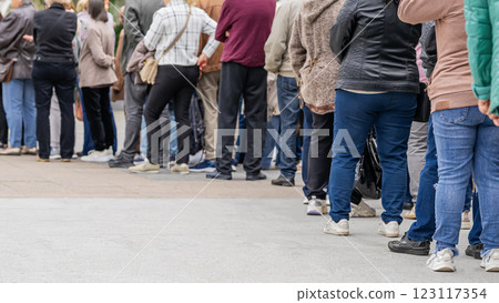 Group of anonymous diverse people standing in queue outdoors, long line of men and women, rear view. Concept of waiting, patience, urban life 123117354