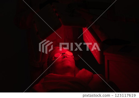 Red light therapy session in a dark treatment room with a patient relaxing Red light therapy session in a dark treatment room with a patient relaxing 123117619