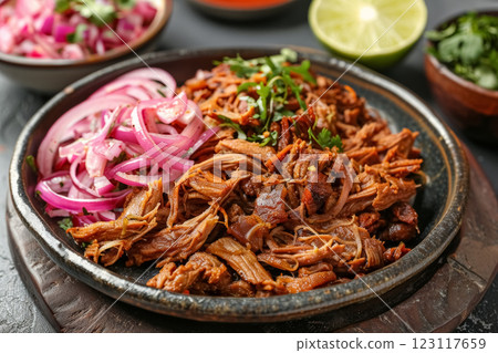 Savory plate of shredded meat slow-cooked beef cochinita pibil garnished with onions and herbs served on dark brown background 123117659