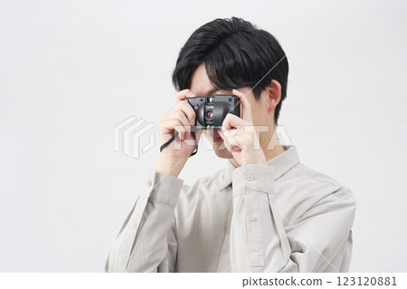Man looking through the viewfinder of a film camera on a white background 123120881