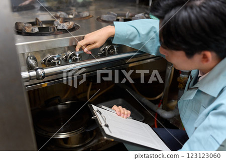 A man checking a gas stove at a restaurant A man checking a gas stove at a restaurant 123123060